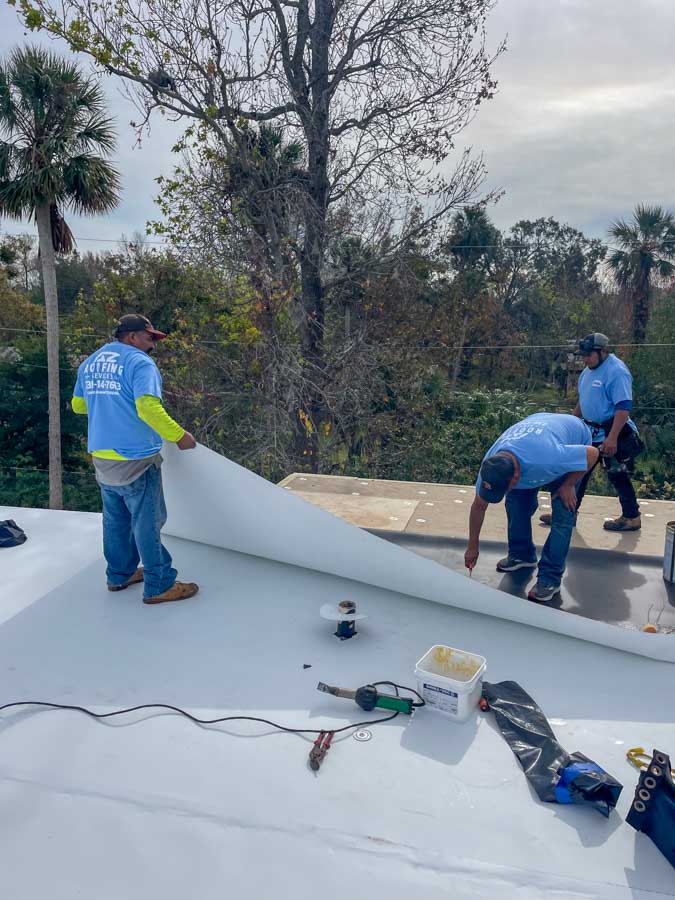 Roofing team installing flat roof membrane