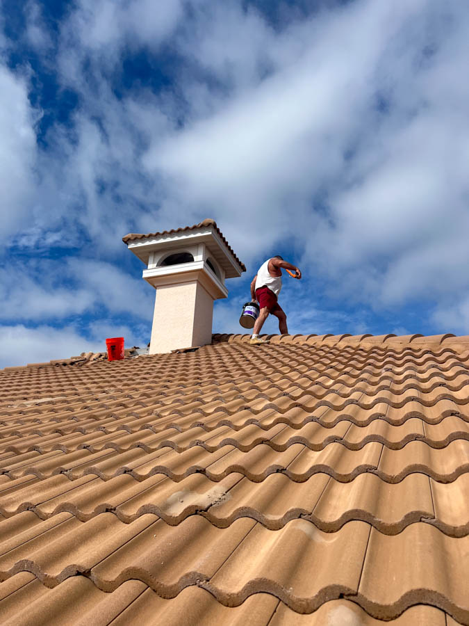 Roofer working on clay tile roof with blue sky
